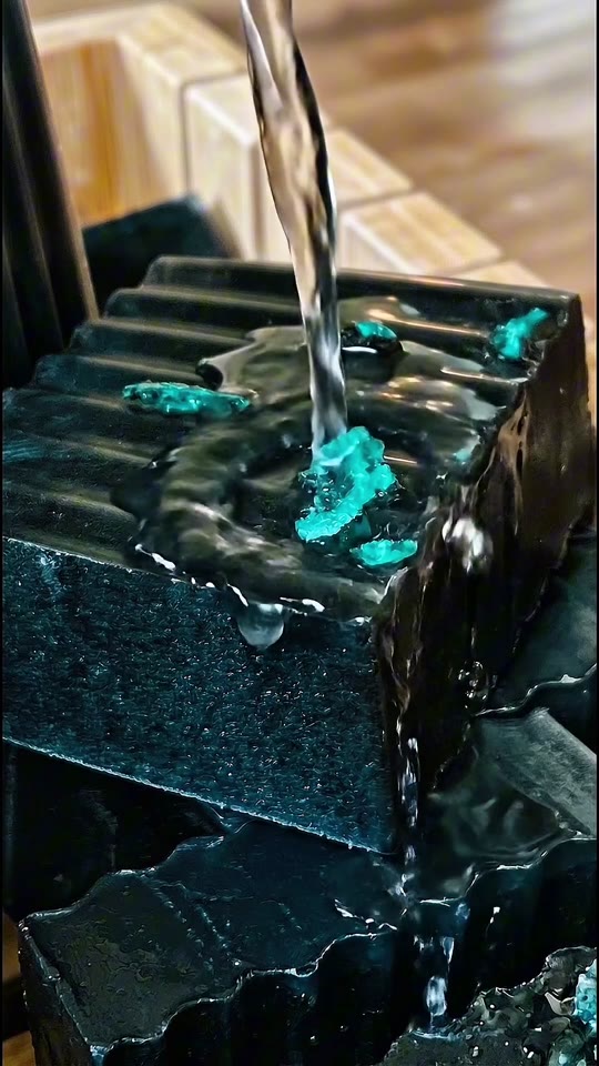 INT body-care commercial frame showing dark sculpted artisan soap with turquoise crystal detail